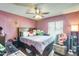 A cozy bedroom with pink walls features a ceiling fan and a comfortable queen bed at 2202 N Los Altos Dr, Chandler, AZ 85224