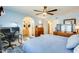 A large bedroom with a view into the bathroom and a work area under a ceiling fan at 2202 N Los Altos Dr, Chandler, AZ 85224