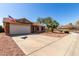 Home exterior featuring a two-car garage, brick accents, desert landscaping, and an American flag at 2251 E Remington Pl, Chandler, AZ 85286