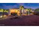 Inviting backyard featuring desert landscaping, covered patio with seating, and exterior lighting for evening enjoyment at 23318 N Las Positas Ct, Sun City West, AZ 85375