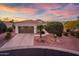 Charming home featuring a tile roof, two-car garage, desert landscaping, and beautiful sunset at 23318 N Las Positas Ct, Sun City West, AZ 85375