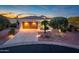 Charming home featuring a two-car garage and meticulously landscaped front yard with warm sunset lighting at 23318 N Las Positas Ct, Sun City West, AZ 85375