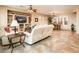 Spacious living room with tiled flooring, white sofas and an entertainment center, open to the dining room at 23318 N Las Positas Ct, Sun City West, AZ 85375