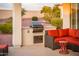 Outdoor kitchen with a built-in grill, seating area, and lush greenery, perfect for outdoor gatherings at 23318 N Las Positas Ct, Sun City West, AZ 85375