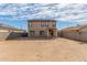 Expansive backyard featuring a two-story home with a covered patio, block wall, and desert landscaping at 25792 W Burgess Ln, Buckeye, AZ 85326