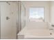 Bright bathroom featuring an enclosed shower and a relaxing soaking tub with a window view at 25792 W Burgess Ln, Buckeye, AZ 85326