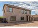 Rear view of a two-story residence featuring a stucco exterior and an open backyard space at 25792 W Burgess Ln, Buckeye, AZ 85326