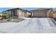 Long driveway leading to a three-car garage, complemented by well-maintained landscaping and stone accents at 25951 N 106Th Dr, Peoria, AZ 85383