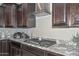 Close-up of the kitchen showcasing granite countertops, a modern range hood, and dark wood cabinetry at 25951 N 106Th Dr, Peoria, AZ 85383