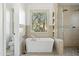 Elegant bathroom featuring a freestanding tub, walk-in shower, neutral tiling, and a large window at 27641 N 74Th St, Scottsdale, AZ 85266