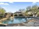 Serene pool area with rock waterfall feature, mature trees and desert landscaping at 27641 N 74Th St, Scottsdale, AZ 85266