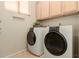 Bright laundry room with side-by-side washer and dryer and storage cabinets at 2909 N 111Th Dr, Avondale, AZ 85392