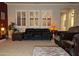 Comfortable living room with a large leather sofa, neutral carpet, and plantation shutters at 3212 E Constance Way, Phoenix, AZ 85042