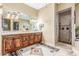 Charming bathroom featuring double sinks with wooden cabinets, a shower, and a large mirror at 3464 E Dartmouth St, Mesa, AZ 85213
