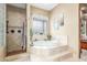 Elegant bathroom featuring a relaxing soaking tub, decorative tile, and a walk-in shower at 3464 E Dartmouth St, Mesa, AZ 85213