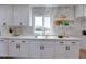 Bright kitchen featuring white cabinets, quartz countertops, and stylish backsplash with stainless steel sink and window at 350 N 9Th St, Coolidge, AZ 85128