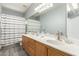 Well-lit bathroom with double sink vanity, large mirror, and shower with gray and white striped shower curtain at 3602 W Barcelona Dr, Chandler, AZ 85226