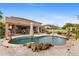 Beautiful pool with rock waterfall features, lush landscaping, and a covered outdoor seating area at 4297 S Marion Pl, Chandler, AZ 85249