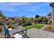 A serene backyard features a stone patio bordered by a grassy area, surrounded by lush landscaping and desert plants at 4483 E Sourwood Dr, Gilbert, AZ 85298