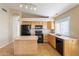 Eat-in kitchen features an island, black appliances, wood cabinets, and a window for natural light at 5125 W Wikieup Ln, Glendale, AZ 85308