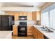 Traditional kitchen with a black refrigerator and range, wood cabinetry, and tile flooring at 5125 W Wikieup Ln, Glendale, AZ 85308