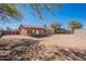 View of the exterior of the home from the large dirt backyard, featuring covered patio at 516 E Mesquite Ave, Apache Junction, AZ 85119