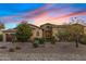 Inviting home exterior with stone accents, a paver driveway, and lush desert landscaping under a colorful sky at 5421 E Juniper Canyon Dr, Cave Creek, AZ 85331