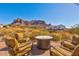 Comfortable outdoor patio seating area with a fire pit table and beautiful mountain views at 5556 E Singletree St, Apache Junction, AZ 85119