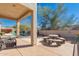 Covered patio with stone table and chairs overlooking a pool and desert landscaping at 7703 E Sayan St, Mesa, AZ 85207