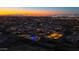 Aerial view of a vibrant residential area with illuminated homes and a sparkling community pool at twilight at 9831 S 11Th St, Phoenix, AZ 85042