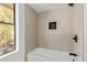 Clean bathroom with a white tub, tiled walls, dark hardware, and a window providing natural light at 10422 N 11Th Pl # 3, Phoenix, AZ 85020