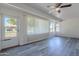 Enclosed sun room with grey wood-look floors, ceiling fan, and large windows showing the outside at 14006 N Tumblebrook Way, Sun City, AZ 85351