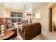 Spacious living room featuring plush brown sofas, a ceiling fan, and a passthrough to the kitchen at 14950 W Mountain View Blvd # 4103, Surprise, AZ 85374