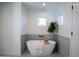 Bright bathroom features a freestanding tub, gray tile accent wall, and natural light from two windows at 15440 N 54Th St, Scottsdale, AZ 85254