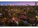 Expansive aerial view of the city, showcasing a red tile roof home amidst lush greenery and palm trees at dusk at 1614 Palmcroft Sw Dr, Phoenix, AZ 85007