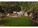 Grassy backyard view showcasing the pool, mature trees, dining area and the home's architecture at 1614 Palmcroft Sw Dr, Phoenix, AZ 85007