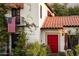 Charming home exterior featuring a striking red front door, Spanish-tile roof, and an American flag displayed on a balcony at 1614 Palmcroft Sw Dr, Phoenix, AZ 85007