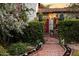 Inviting front entrance with a red-brick pathway leading to a gated courtyard of a charming white home at 1614 Palmcroft Sw Dr, Phoenix, AZ 85007