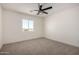 Bright bedroom features soft carpet, a window with views, and a modern ceiling fan at 16560 N Slate Ln, Maricopa, AZ 85139