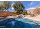 Inviting pool area featuring a rock waterfall and desert landscaping, creating a serene backyard oasis at 17560 W Desert View Ln, Goodyear, AZ 85338