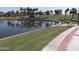 Scenic community lake view with grass areas, lake, and paved paths providing a picturesque outdoor space at 17560 W Desert View Ln, Goodyear, AZ 85338