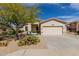 Beige single-story home featuring desert landscaping, mature tree, and a two-car garage at 17560 W Desert View Ln, Goodyear, AZ 85338