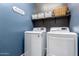 Well-organized laundry room features a washer, dryer, storage shelves and decor at 17577 W Desert Bloom St, Goodyear, AZ 85338