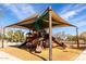 A vibrant playground with a sunshade canopy and a variety of play equipment at 17577 W Desert Bloom St, Goodyear, AZ 85338