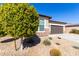 Single-story home with desert landscaping and a two-car garage, partially obscured by a tree at 17588 W Maricopa St, Goodyear, AZ 85338