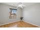 Well-lit bedroom with hardwood floors, neutral walls, and a window overlooking a quiet street at 19595 N 107Th Dr, Sun City, AZ 85373