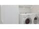 Bright laundry room featuring a white washer and dryer set with a built-in shelf and a nearby refrigerator at 19595 N 107Th Dr, Sun City, AZ 85373