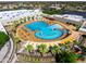 Aerial view of a vibrant outdoor community pool featuring ample seating, tropical trees and colorful awnings at 21402 N 158Th Dr, Sun City West, AZ 85375