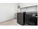 Modern laundry room features gray washer and dryer, plus a utility sink and open shelf at 21978 N 97Th Dr, Peoria, AZ 85383