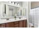 Bathroom with double vanity, large mirror, and shower with white curtain and neutral tile flooring at 2215 E La Costa Dr, Gilbert, AZ 85298